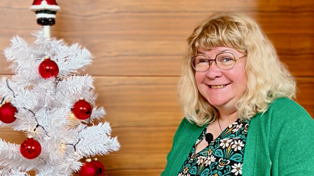 augenblicke | weißer Weihnachtsbaum Eine Frau steht mit einer grünen Weihnachtskugel in der Hand vor einem weißen geschmückten plastik Weihnachtsbaum
